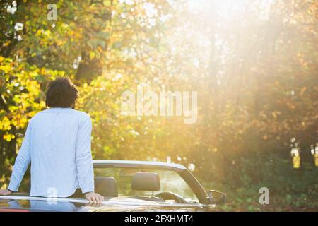 Carefree young man in convertible in sunny idyllic autumn park Stock Photo