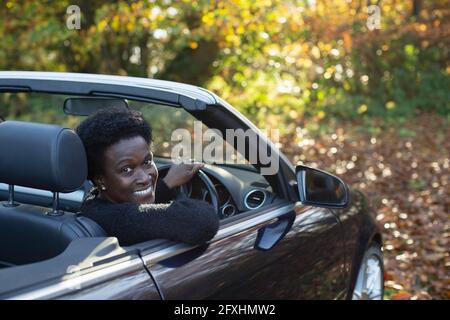 Portrait happy woman driving convertible in autumn park Stock Photo