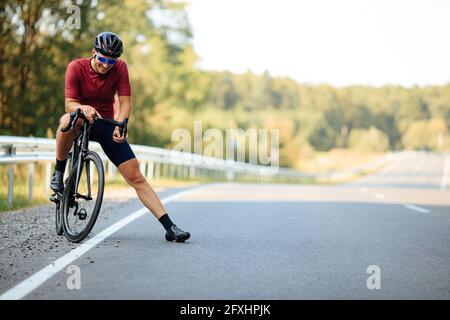 Smiling man with strong legs posing on camera with bike Stock Photo
