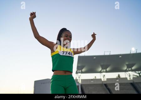 Happy female track and field athlete celebrating at competition Stock Photo