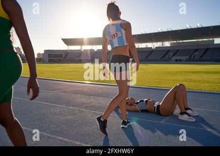 Tired female track and field athlete laying on track after competition Stock Photo