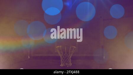 Composition of basketball basket with blue spots of light with prism on yellow tinted background Stock Photo