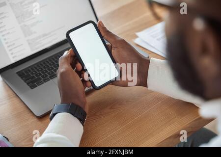 Smartphone white blank screen in male african american hand overhead view Stock Photo