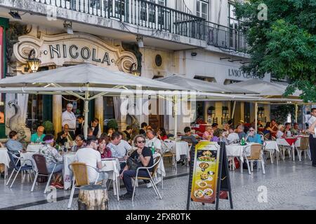 Historic Cafe Nicola entrance with art deco facade and seated customers at outdoor tables in Rossio Square, Lisbon, Portugal, Europe Stock Photo