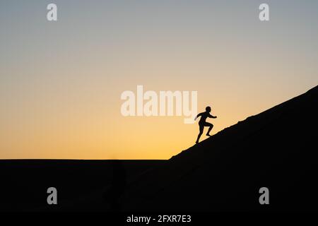 Silhouette of a man running up a sand dune in Nags Head, North Carolina United States of America, North America Stock Photo