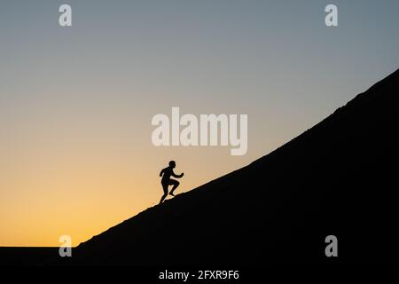 Silhouette of a man running up a sand dune in Nags Head, North Carolina, United States of America, North America Stock Photo