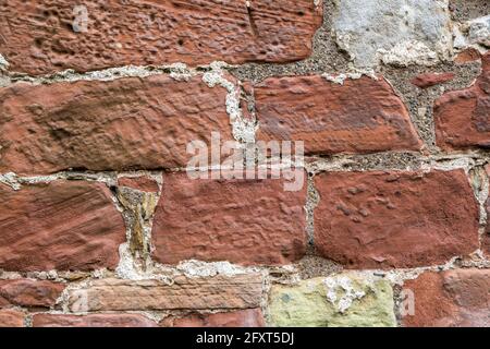 Weathered red stone with plaster remains in wall of Lanercost Priory, Cumbria, England, UK Stock Photo