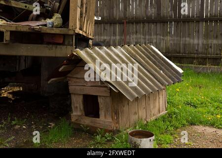 Wooden old doghouse in the grass near the house.one old empty wooden doghouse Stock Photo