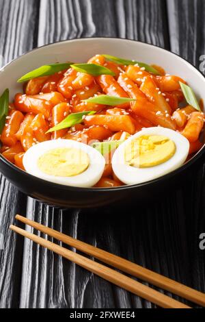 Tteokbokki is one of the most popular Korean street foods in Korea close-up in a bowl on the table. Vertical Stock Photo