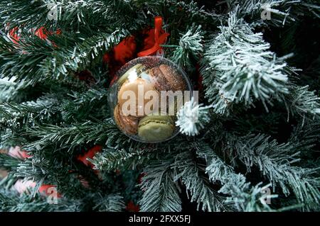Christmas tree toy. The ball hangs on the tree. The ball is filled with makroons Stock Photo