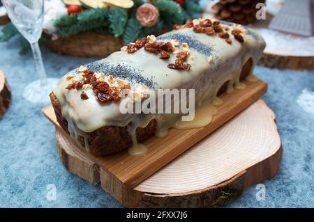 Christmas cake with dried fruit poppy seeds and nuts. White chocolate frosting. Detail of the festive table Stock Photo