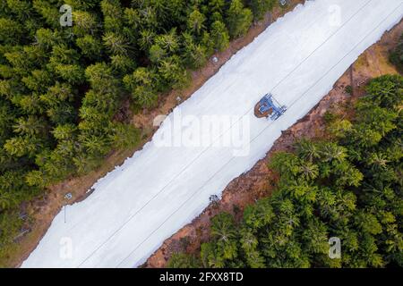 an artificially snowed ski slope in a forest from above Stock Photo