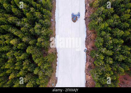 an artificially snowed ski slope in a forest from above Stock Photo