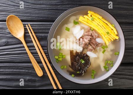 Tteokguk or sliced rice cake soup is a traditional Korean dish eaten during the celebration of the Korean New Year closeup in the bowl on the table. H Stock Photo