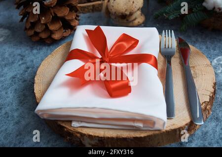 A white napkin tied with a red ribbon lies on a wooden tray. Festive Christmas table server Stock Photo