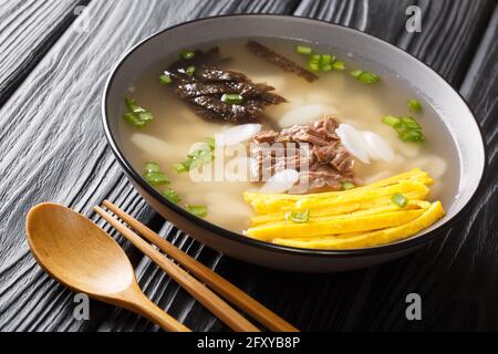 Tteokguk or sliced rice cake soup is a traditional Korean dish eaten during the celebration of the Korean New Year closeup in the bowl on the table. H Stock Photo