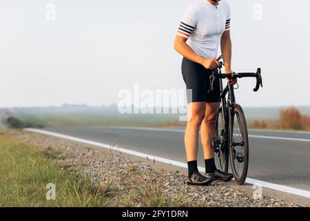 Close up of professional cyclist repairing bike on road Stock Photo