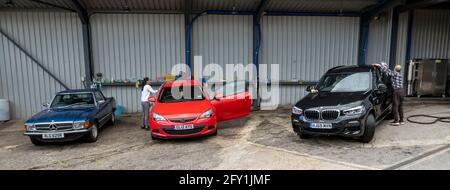 Hampshire, England, UK. 2021. Workers washing and polishing cars, the finishing, drying and polishing area. Stock Photo