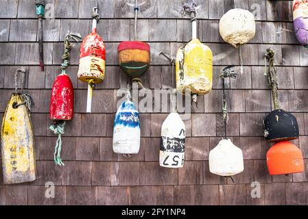 Close up of old lobster buoys hanging on weathered wooden exterior wall of a fishing hut Stock Photo