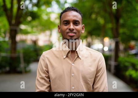 Portrait of handsome black young African businessman outdoors at park Stock Photo