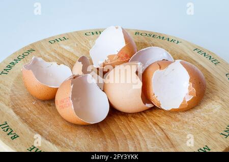 The empty shells of four eggs on a wooden chopping board Stock Photo