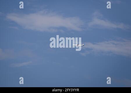 Propeller plane lit by the sun against a blue sky with white clouds and ...