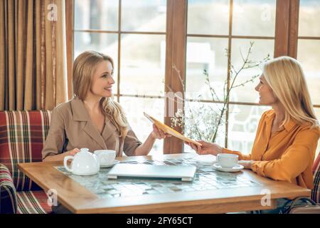 Two women talking and discussing something while sitting at the table in a cafe Stock Photo