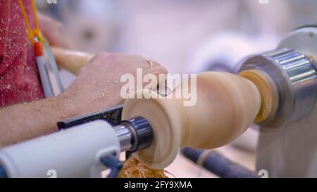 Close up: carpenter using chisel for shaping piece of wood on lathe Stock Photo