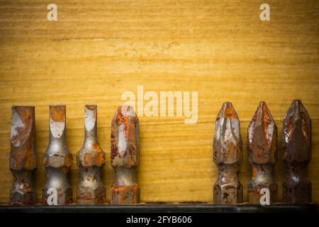 Close up shot of some used rusty screwdriver heads and bits on a wooden background. Stock Photo