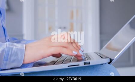 Close up side view - woman hands typing on laptop computer keyboard Stock Photo