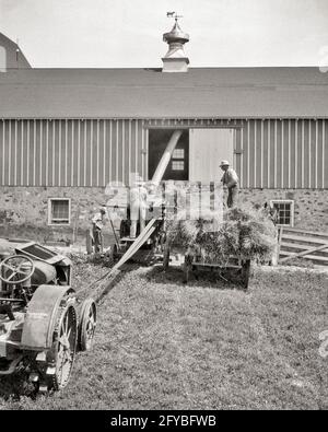 1920s 1930s 1940s THREE MEN FARM WORKERS LOADING HAY INTO BARN USING PITCHFORKS AND A TRACTOR BELT DRIVE MECHANICAL CONVEYOR - f3937 HAR001 HARS WHEELS MECHANICAL SENIOR MAN TRANSPORTATION SENIOR ADULT MIDDLE-AGED AGRICULTURE B&W NORTH AMERICA MIDDLE-AGED MAN LOADING NORTH AMERICAN SKILL OCCUPATION SKILLS MAMMALS AND EXTERIOR FARMERS A INTO OCCUPATIONS USING MOTION BLUR CUPOLA CONVEYOR WAGONS COOPERATION FARM MACHINERY HAYLOFT K3 MAMMAL BLACK AND WHITE CAUCASIAN ETHNICITY HAR001 OLD FASHIONED Stock Photo