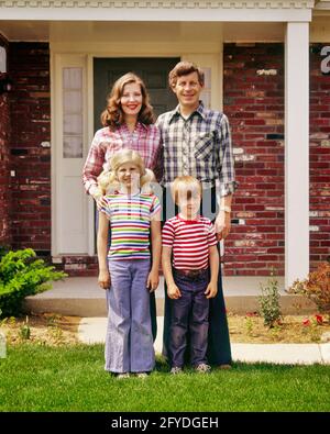 1970s TYPICAL CAUCASIAN AMERICAN FAMILY STANDING IN FRONT OF SUBURBAN BRICK HOUSE MOTHER FATHER SON DAUGHTER LOOKING AT CAMERA - kj7988 HAR001 HARS WIFE LADY HUSBAND DAD FOUR MOM CLOTHING NOSTALGIC PAIR 4 COMMUNITY SUBURBAN COLOR JEANS MOTHERS OLD TIME NOSTALGIA BROTHER OLD FASHION SISTER 1 JUVENILE STYLE WELCOME COTTON DESIGN SONS PLEASED FAMILIES JOY LIFESTYLE SATISFACTION ARCHITECTURE BRICK FEMALES HOUSES MARRIED BROTHERS SPOUSE HUSBANDS HEALTHINESS HOME LIFE UNITED STATES COPY SPACE FRIENDSHIP FULL-LENGTH LADIES DAUGHTERS PERSONS RESIDENTIAL UNITED STATES OF AMERICA MALES BUILDINGS STRIPES Stock Photo