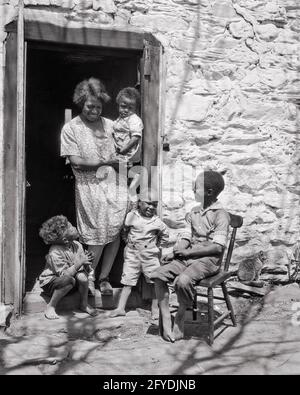 1930s SINGLE SMILING AFRICAN AMERICAN WOMAN MOTHER WITH FOUR CHILDREN STANDING IN DOORWAY OF WHITEWASHED LAID STONE HOME - n946 HAR001 HARS STONE DOORWAY MOTHERS OLD TIME NOSTALGIA BROTHER OLD FASHION JUVENILE STYLE COMMUNICATION INFANT JOY LIFESTYLE FIVE ARCHITECTURE FEMALES HOUSES 5 BROTHERS POOR RURAL HOME LIFE UNITED STATES COPY SPACE FRIENDSHIP FULL-LENGTH LADIES PERSONS RESIDENTIAL UNITED STATES OF AMERICA CARING MALES BUILDINGS SIBLINGS B&W NORTH AMERICA NORTH AMERICAN HAPPINESS PROPERTY AFRICAN-AMERICANS AFRICAN-AMERICAN EXTERIOR SOUTHEAST BLACK ETHNICITY PRIDE IN OF HOMES SIBLING Stock Photo