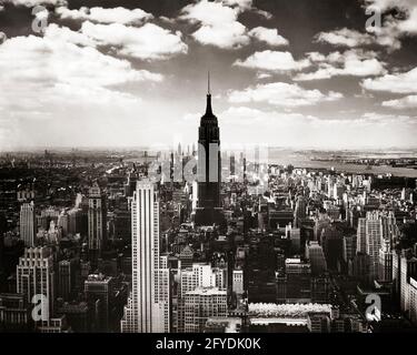 1950s EMPIRE STATE BUILDING SILHOUETTED LOOKING SOUTH FROM THE RCA BUILDING AT ROCKEFELLER CENTER MIDTOWN MANHATTAN NYC USA - r1967 HAR001 HARS EXCITEMENT EXTERIOR GOTHAM OPPORTUNITY NYC REAL ESTATE NEW YORK STRUCTURES CITIES ROCKEFELLER STYLISH EDIFICE NEW YORK CITY ANTENNA BLACK AND WHITE HAR001 OLD FASHIONED RCA Stock Photo