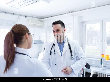 Man and woman in hospital laboratory lab greeting. Two young doctors clinicians smiling at clinic. Stock Photo