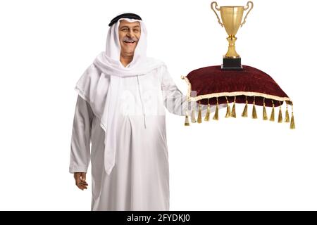 Mature arab man holding a trophy cup on a red velvet cushion isolated on white background Stock Photo