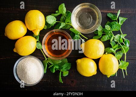 Kentucky Lemonade Cocktail Ingredients: Bourbon, sugar, mint, and lemons on a dark wood background Stock Photo