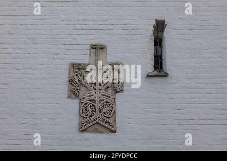 Wall of an Orthodox church made of white bricks with a window and a fragment of an old pattern. Stock Photo