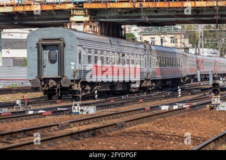 An old long-distance train passes under a shabby rusty bridge. Stock Photo