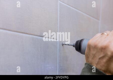 Carpenter in work on drilling hole in bathroom wall for installing bathroom accessories Stock Photo