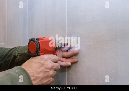Professional construction tools in handyman working with drill tile in bathroom Stock Photo