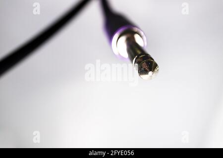 Macro Closeup of Tip on Quarter Inch Jack Dangling From Cable Against White Background Stock Photo