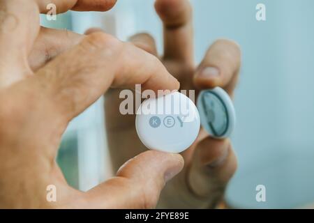 Man pov looking at AirTag with printed Key text reflected rear surface Stock Photo