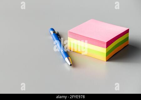 Blank sticky paper notepad and pen on a gray table. Stock Photo