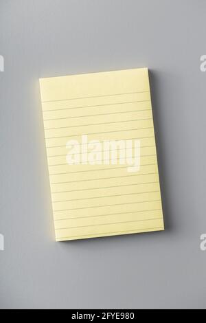 Blank sticky paper notepad on gray table. Top view. Stock Photo