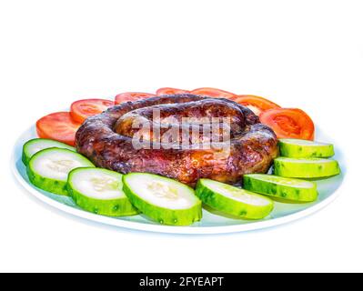 Smoked meat sausage on a plate with tomatoes and cucumbers. Stock Photo