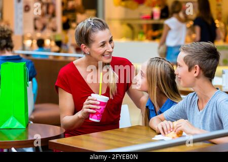 Family eating and drinking in cafe at shopping mall Stock Photo