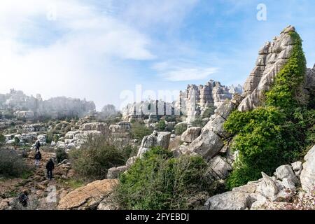 a view of tourists walking around the weather eroded peaks and valleys of Torcal in Antequera Stock Photo