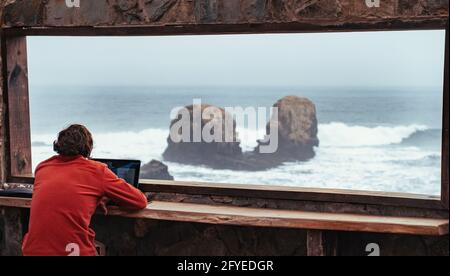 man working on the beach, working on his computer, Pichilemu, punta de lobos, chile. Stock Photo