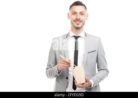 Horizontal medium portrait of handsome young adult Caucasian man wearing gray suit having lunch looking at camera, white background Stock Photo